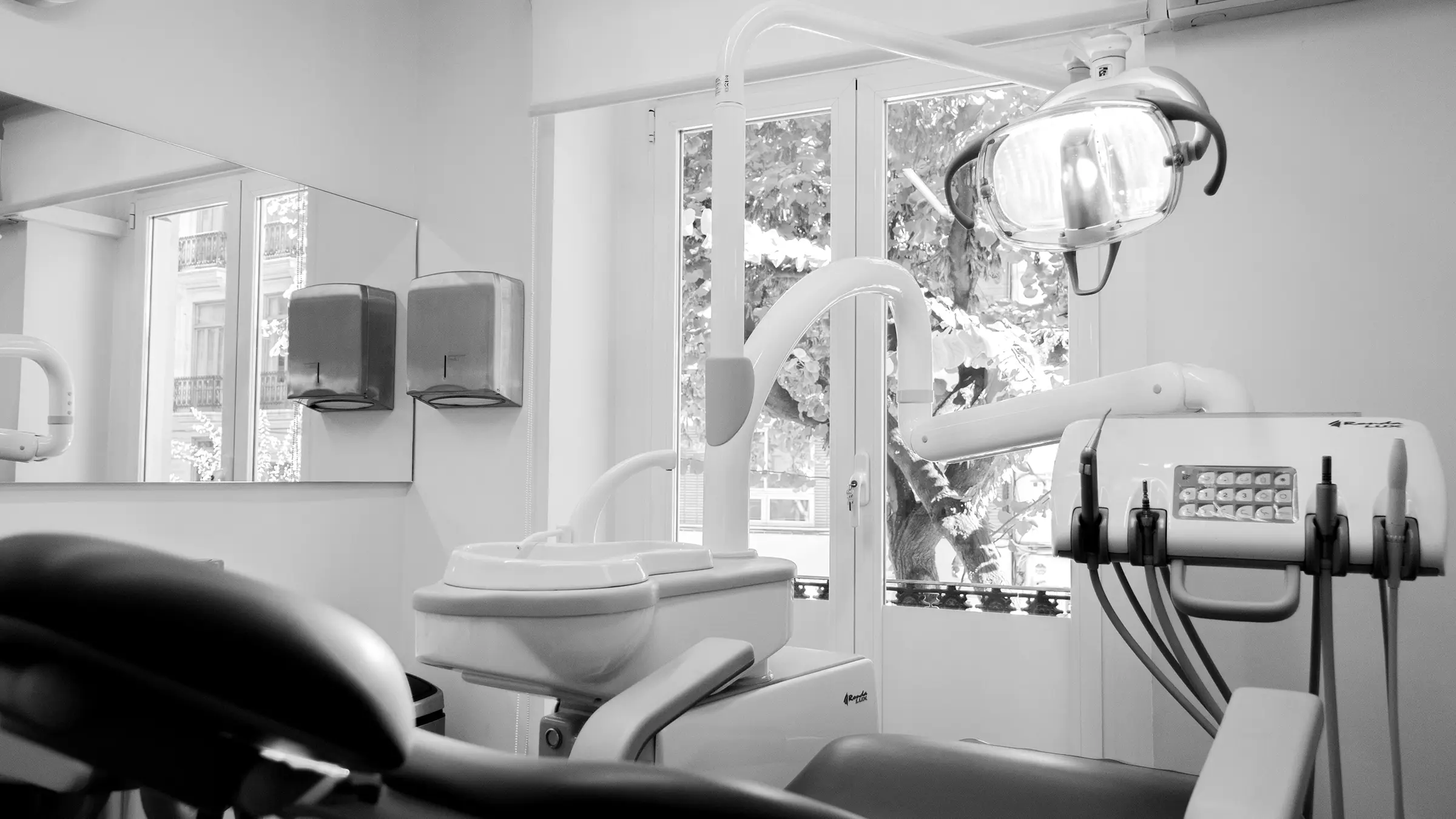 Treatment room with the window open onto the plane trees of Calle Cirilo Amorós